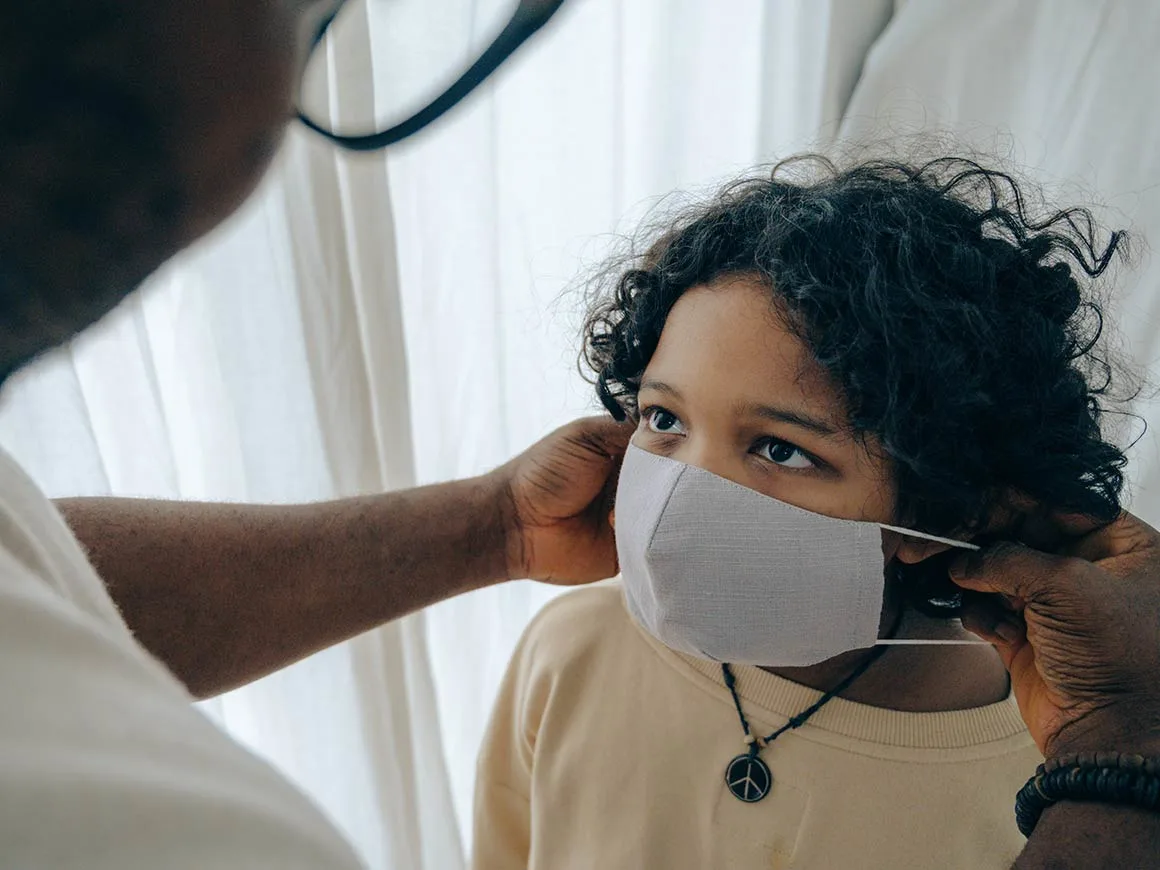 Parent putting face mask on child